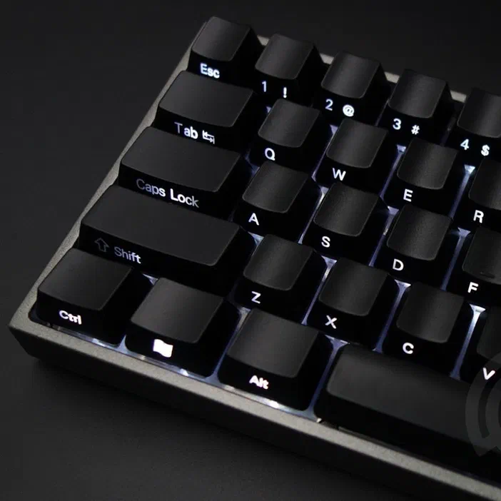 Vue rapprochée d'un clavier informatique avec des touches noires à texte blanc et un rétroéclairage bleu sous les claviers.
