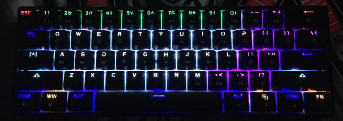 Clavier mécanique à touches noires avec un rétroéclairage RGB multicolore qui s'échappe par les bords des touches.