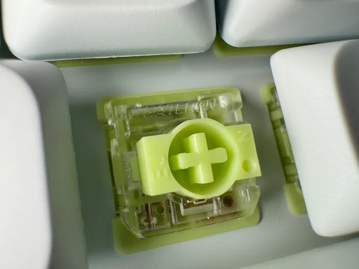 Détail d'un switch de clavier mécanique avec une base transparente et des composants internes en plastique vert clair portant l'inscription Gateron.