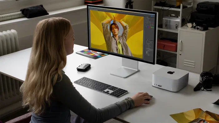Sur son écran, une femme retouche une photographie en utilisant les outils d'un logiciel de traitement d'image dans un espace informatique moderne.