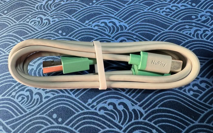 Un câble USB-C beige aux connecteurs verts portant l'inscription NuPhy.