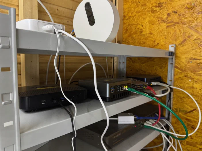 Un rack informatique avec plusieurs serveurs et routeur connectés par des câbles Ethernet blancs, rouges et verts.