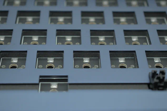 Vue rapprochée d'un clavier mécanique bleu avec des interrupteurs visibles dans chaque case.