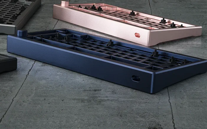 Deux boîtiers de clavier mécaniques Akko en aluminium bleu et rose vus sur un sol gris.