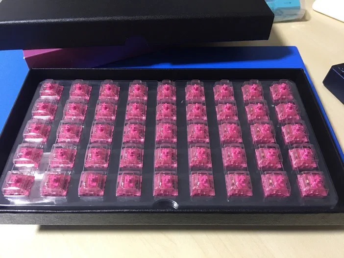 Un emballage noir contenant des touches de clavier rose vif disposées en grille.