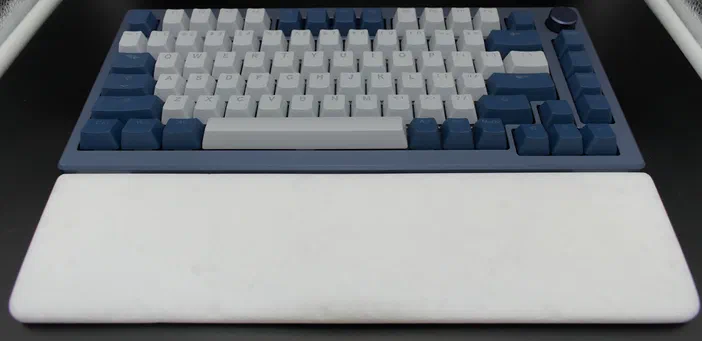 Clavier mécanique complet avec des touches blanches et bleues sur un socle bleu, accompagné d'un repose-poignet blanc.
