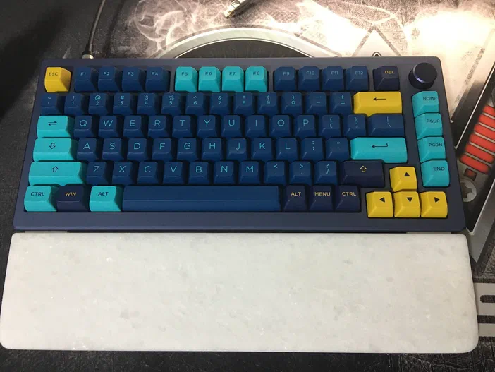 Clavier mécanique avec touches bleues et cyan, repose sur un tapis de souris blanc.