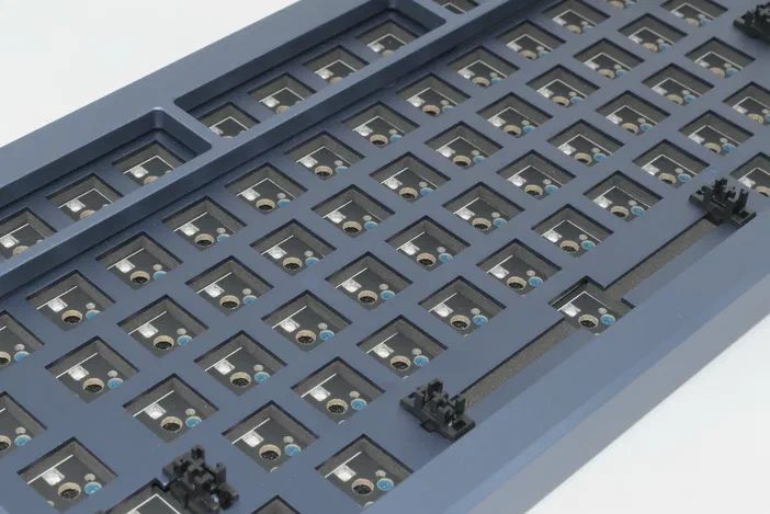 Vue rapprochée d'un clavier mécanique montrant les sockets noirs pour switches installés dans une rangée de touches.