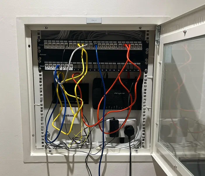 Un cabinet de réseau avec des câbles colorés connectés à un panneau de commutation.