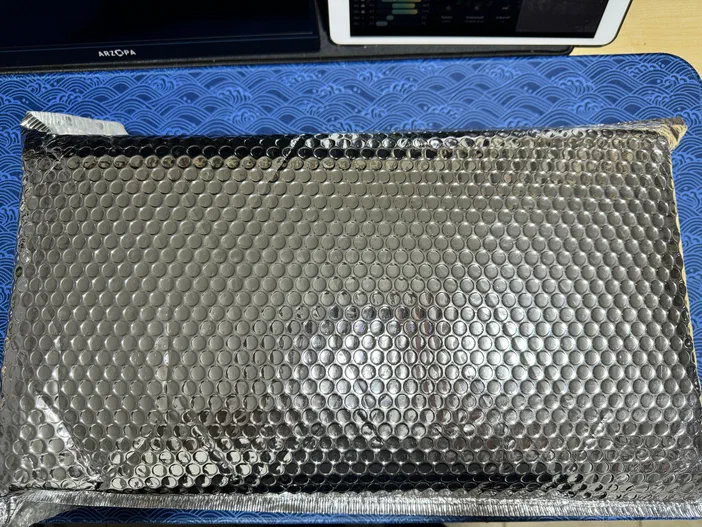 Un emballage protecteur épais et robuste, de couleur argentée avec une texture en bulles hexagonales.