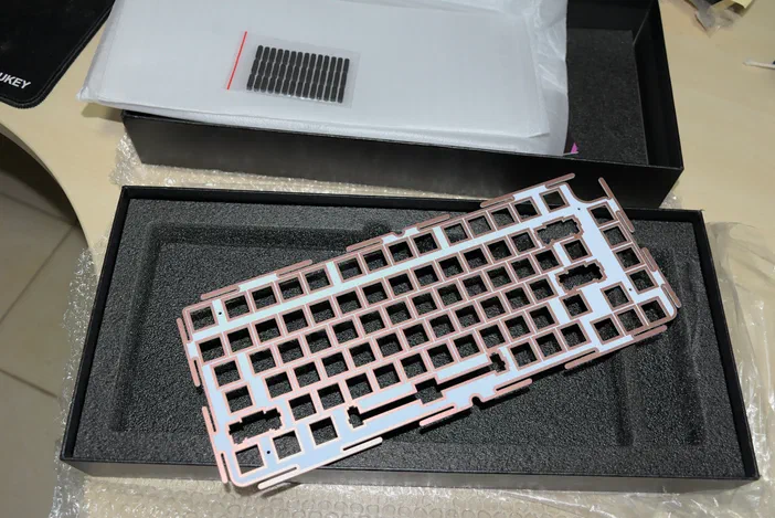 Plaque de clavier en plastique rose et blanc dans un emballage noir avec mousse protectrice