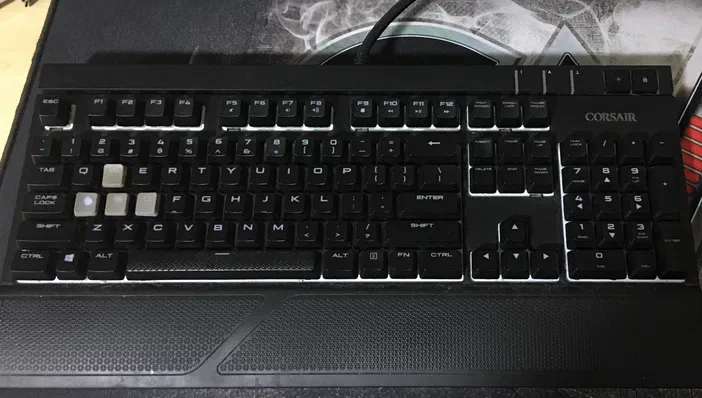 Clavier mécanique noir Corsair avec touches blanches et grises sur un tapis de souris.