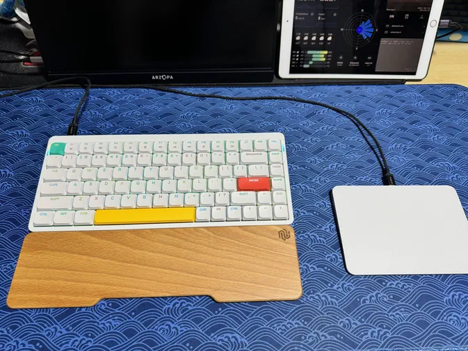 Clavier Nuphy Air75 V2 blanc avec touches colorées et repose-pouces en bois sur tapis bleu